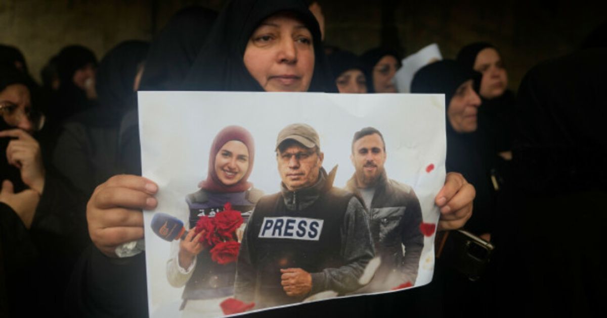 A woman holds a poster of Ali Shoes (front), Fatima Ftouni and Mohammad Ftouni during their funeral on Sunday, 29 March 2026 (Photo/Alamy)